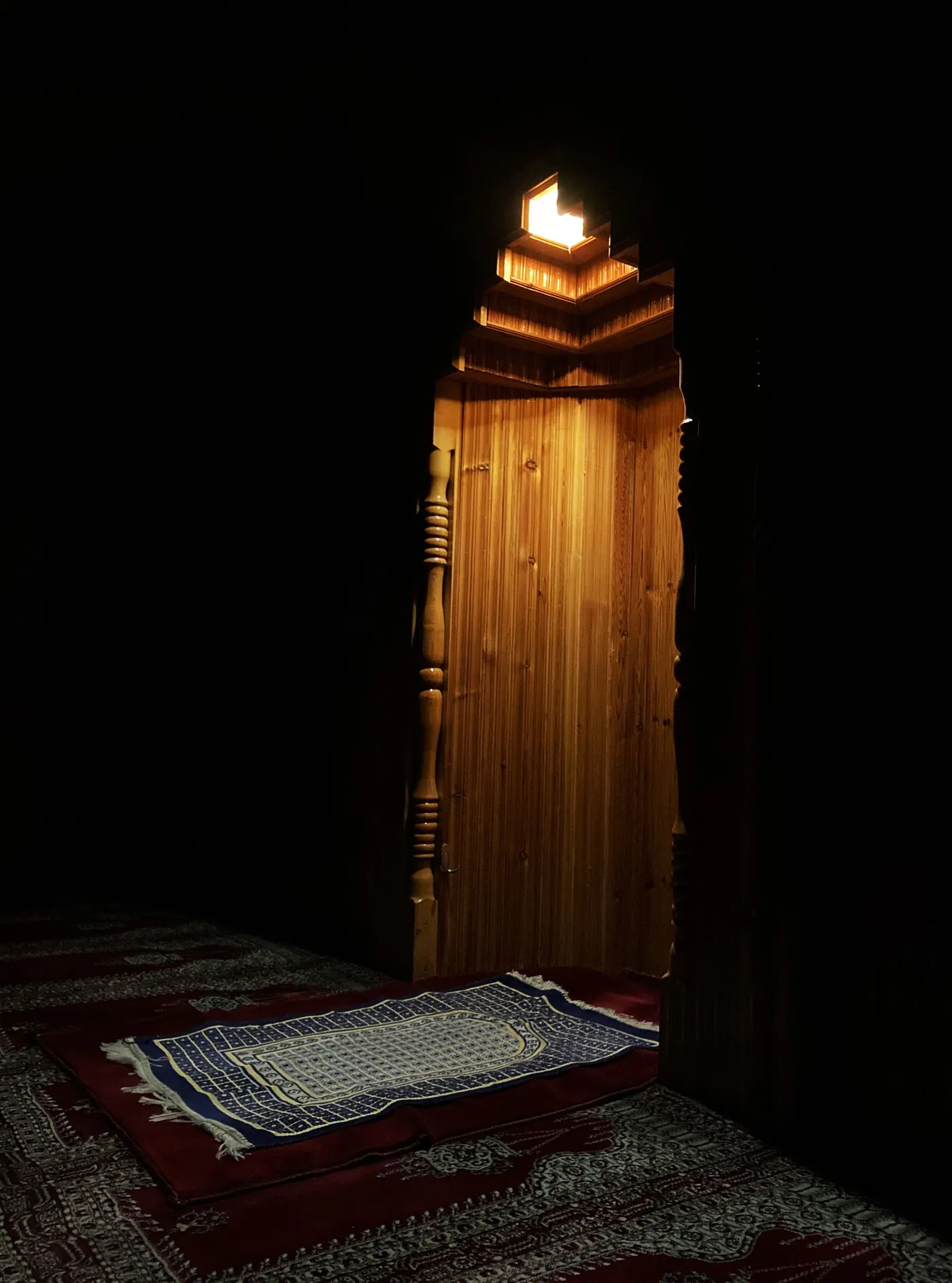 Une niche de mihrab éclairée dans la pénombre d'une salle de prière