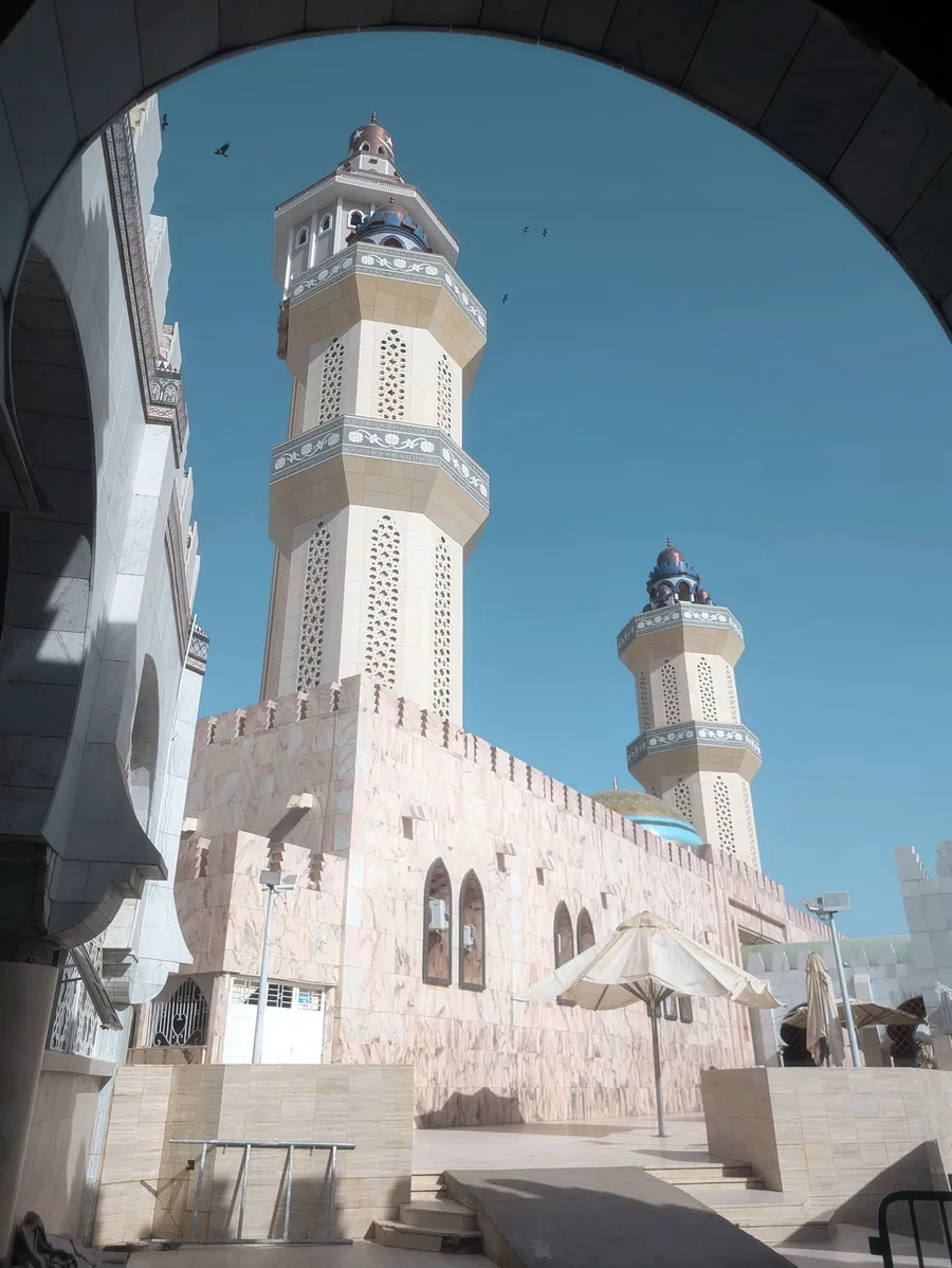 Vue rapprochée en contre-plongée des minarets de la Grande Mosquée de Touba sous un ciel bleu