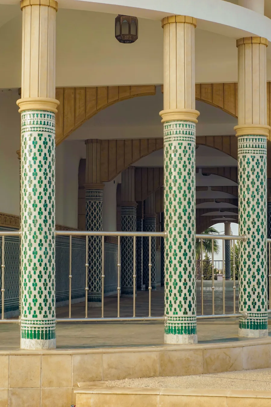Colonnes couvertes de mosaïques vertes et blanches dans une galerie de la Grande Mosquée de Touba
