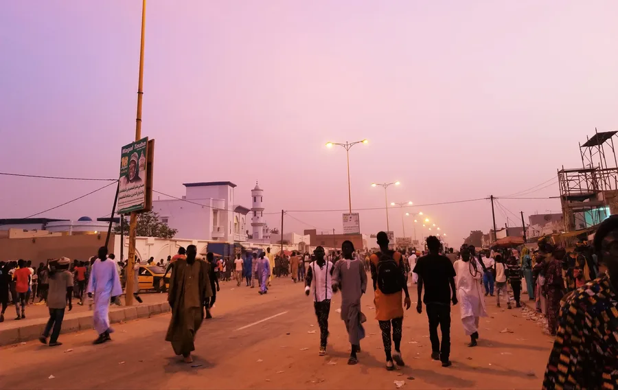 Foule marchant dans une rue de Touba au crépuscule pendant le Grand Magal
