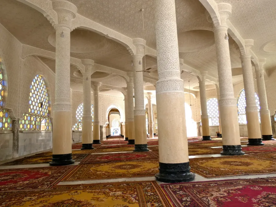 Galerie à colonnades vide de la Grande Mosquée de Touba, tapis rouges et jaunes au sol