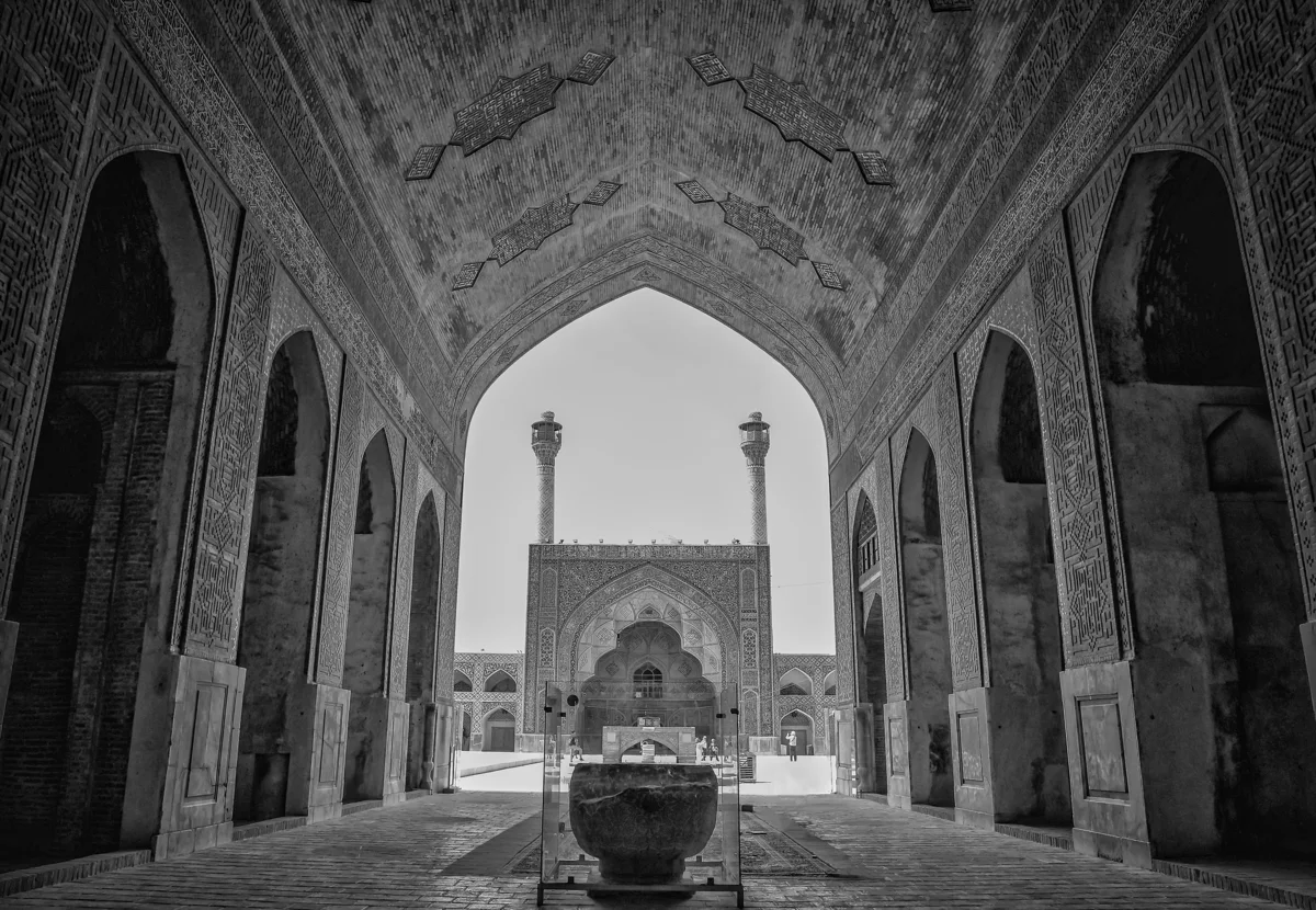 Vue en noir et blanc depuis un iwan de la Grande Mosquée du Vendredi d'Ispahan vers la cour et les minarets jumeaux de l'iwan sud
