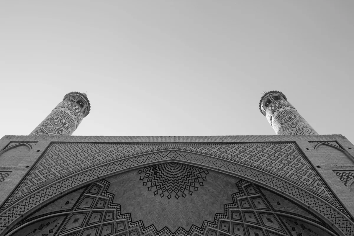 Vue en contre-plongée en noir et blanc des deux minarets et de l'arc du portail de la Grande Mosquée du Vendredi d'Ispahan