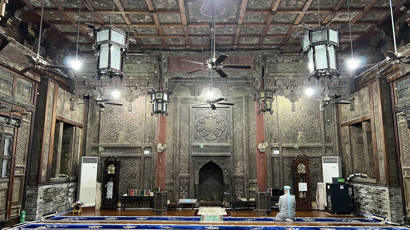 Grande Mosquée de Xi'an — intérieur de la salle de prière avec le mihrab sculpté et un fidèle en prière